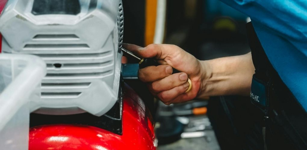 Mécanicien réparant un compresseur rouge dans un atelier